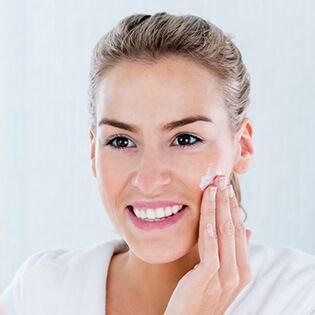 woman applying face cream after treatment